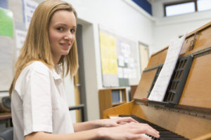 Schoolgirl playing piano in music class